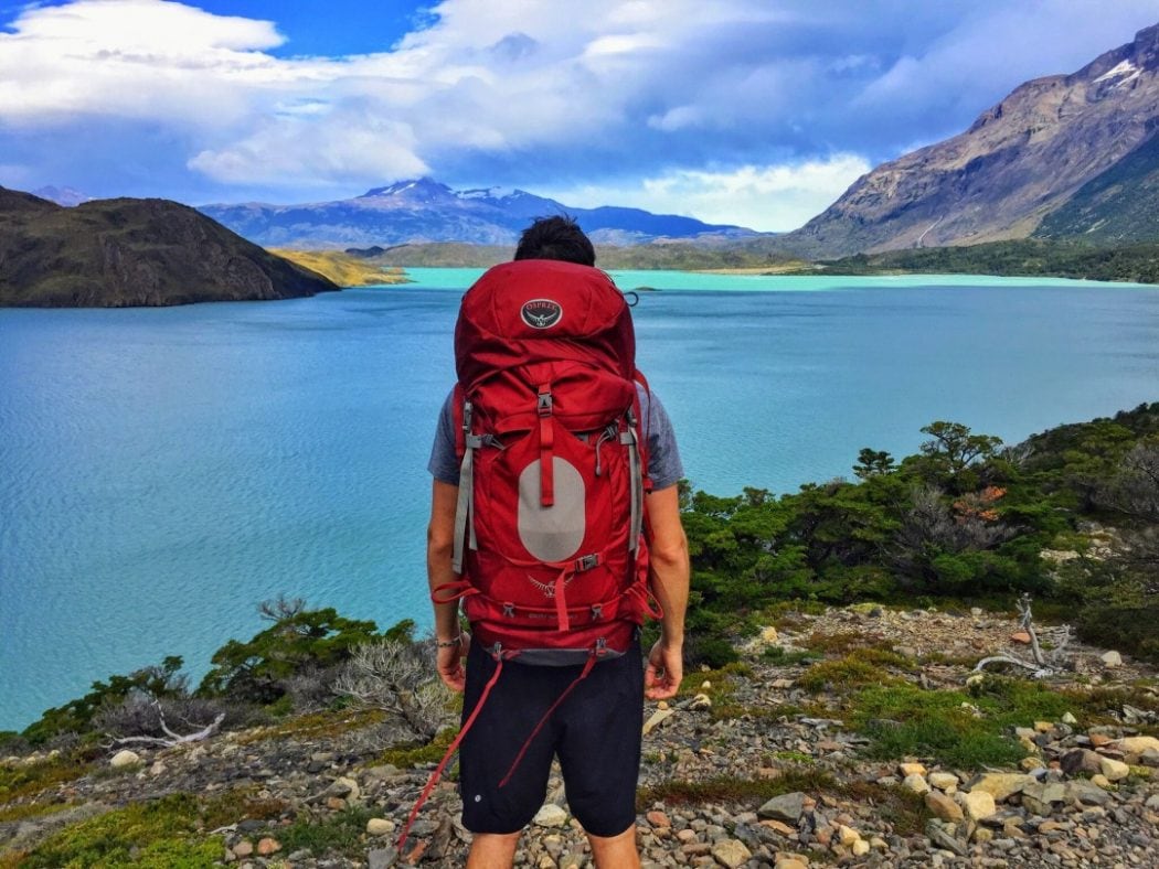 一名男子背着他最好的旅行背包在勘察一个湖泊