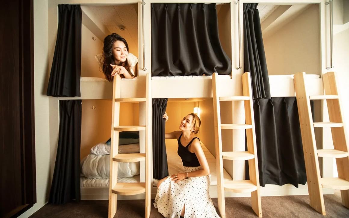 Two solo female travellers chatting in a hostel dorm in Japan