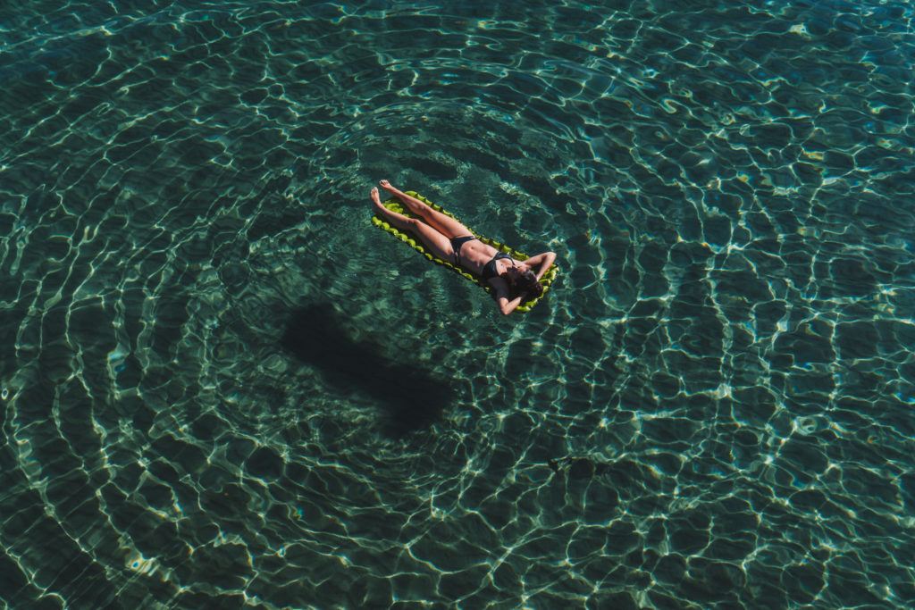 女孩漂浮在蓝色的水休息，从太多的旅行