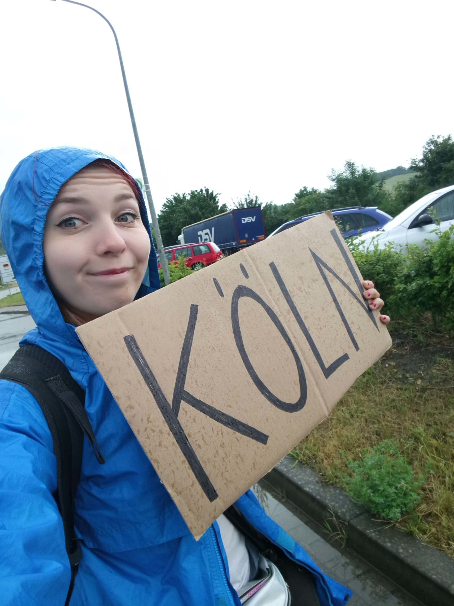girl hitchhiking in a blue raincoat