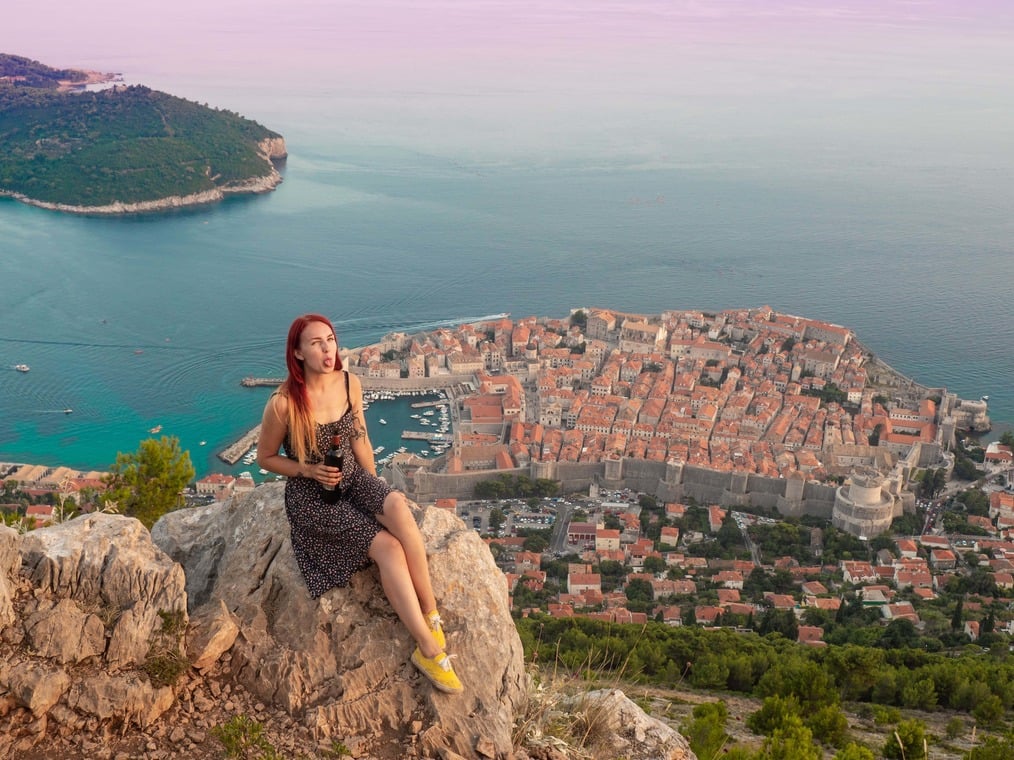solo female backpacker looking over Dubrovnik, Croatia with a bottle of wine in hand