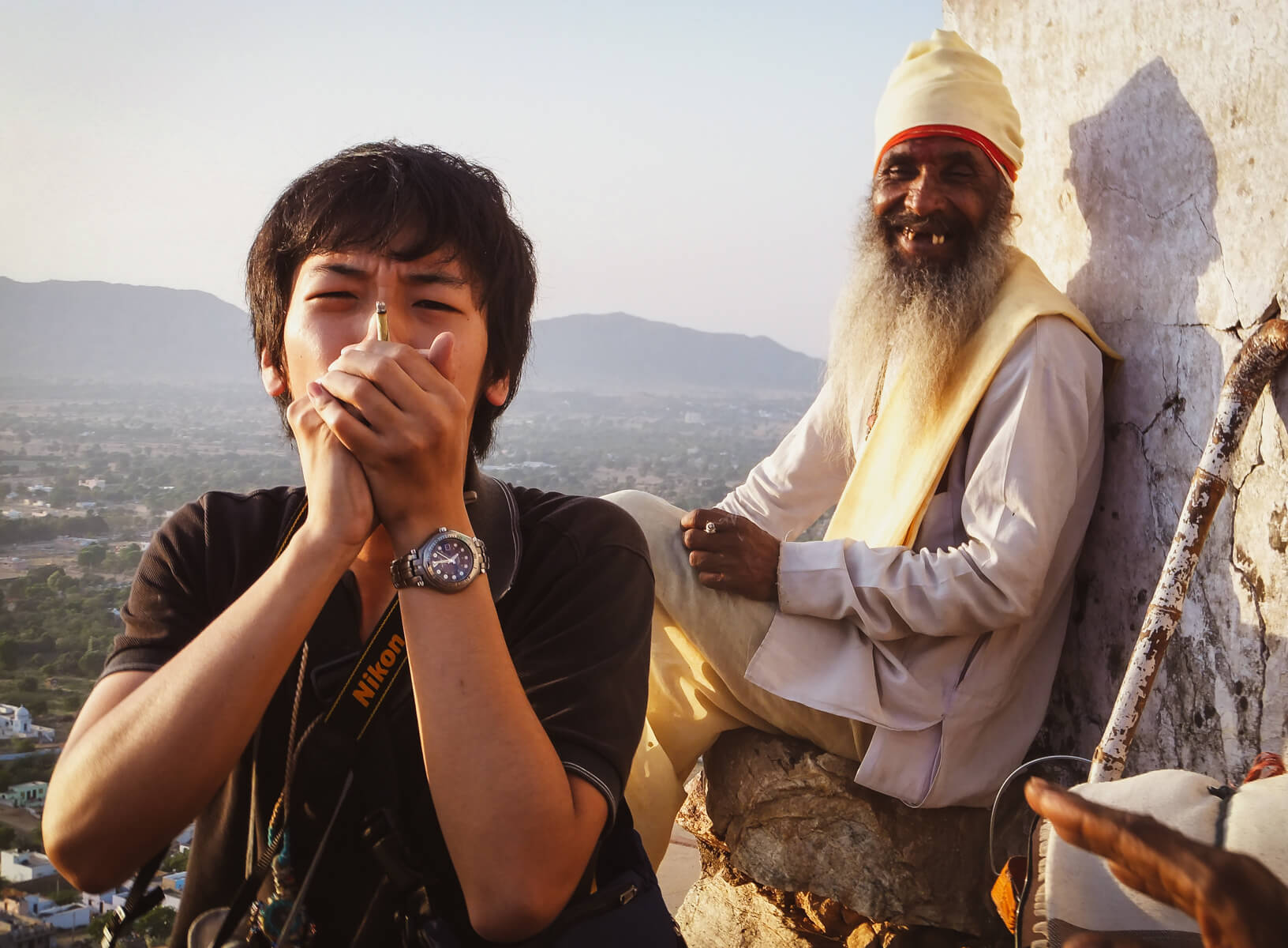 在印度旅行的背包客和当地的一位老人一起抽大麻