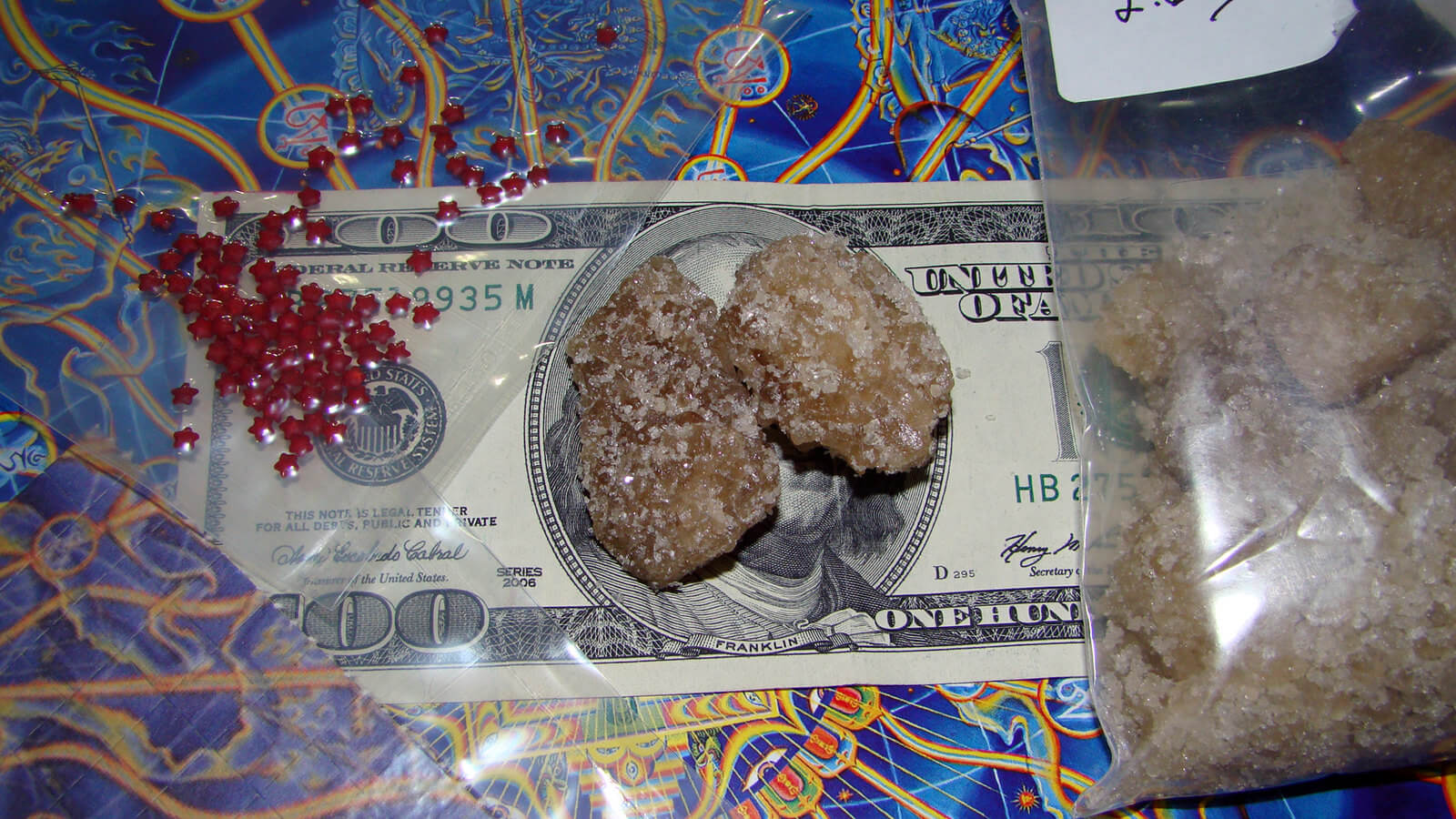 在路上买的毒品——MDMA晶体和一些LSD微粒放在一张100美元的钞票上