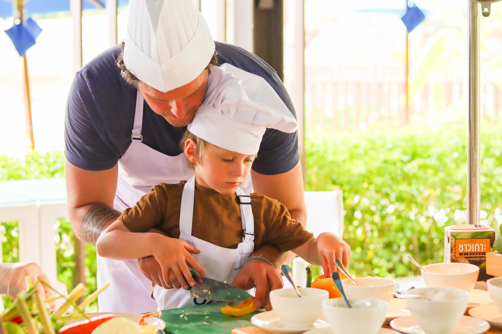 戴着白色厨师帽的孩子和爸爸一起学做菜